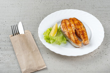 Salmon teriyaki steak with lemon and lettuce.