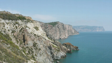 Fototapeta na wymiar Picturesque coast with rocky cliffs and blue sea. Action. Seascape with rocky coast. Amazing beauty of rocky coast of Black Sea in Crimea