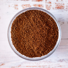 Close-up view of freshly ground coffee on a rustic white table