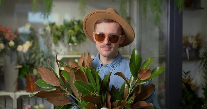 Mother's Day, Valentine's Day or International Women's Day concept. Smiling hipster male person in sunglasses and hat with fresh spring flower bouquet and welsh corgi dog. High quality 4k video