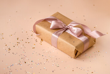 Valentines Day, Birthday or New Year present in kraft paper with pink ribbon on soft beige...