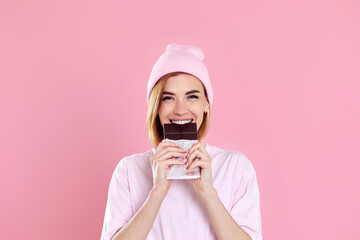 young happy woman in casual t-shirt biting sweet chocolate bar