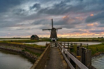Dramatic shot of the Kagerplassen windmill by a small lake during sunset with a pinkish sky