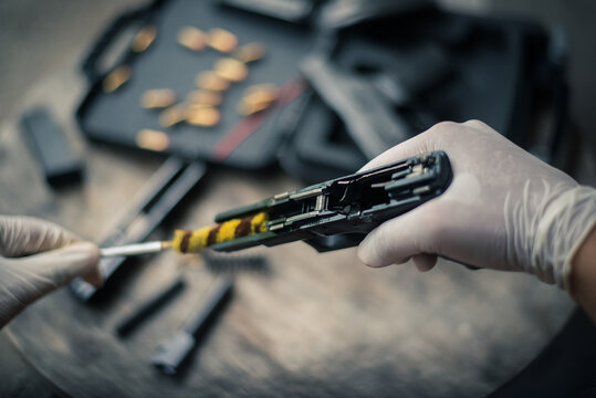 The gunsmith is sitting around cleaning the gun and disassembling and maintaining the pistol.