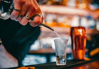 bartender pouring alcohol into a shot glass in bar