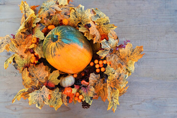 ripe pumpkin and decorative bright autumn wreath on wooden background. fall season concept. Symbol of Thanksgiving day, Halloween, Autumn harvest. top view