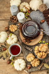 Autumn tea concept. Cookies with pumpkin puree, black tea in a glass teapot, fall decor