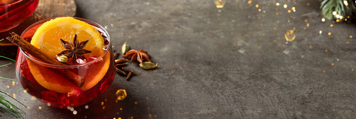 Mulled wine glass decorated with cinnamon and anise on conrete background. Festive food banner....