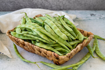 Ripe green beans. Fresh and raw green beans in basket on stone background. Organic food. close up