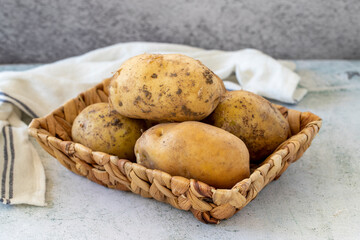 Ripe Potatoes. Fresh and raw potatoes in a basket on a stone floor. Organic food. close up