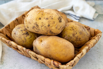 Ripe Potatoes. Fresh and raw potatoes in a basket on a stone floor. Organic food. close up