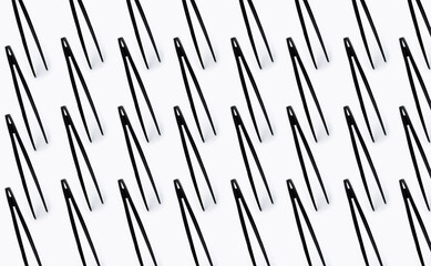 Pattern of black plastic toongs on white background.