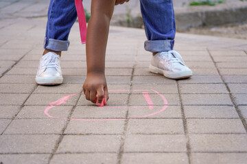 girl drawing with chalk on the school playground floor. - obrazy, fototapety, plakaty