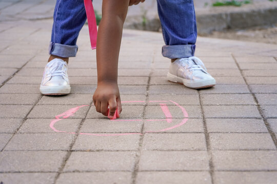 Girl Drawing With Chalk On The School Playground Floor.