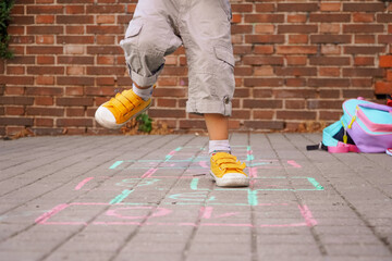 boy playing hopscotch on school playground. back to school concept.