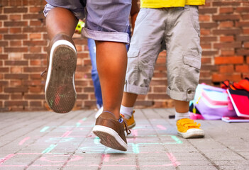multiethnic kids playing hopscotch on school playground.