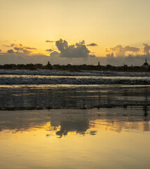 A beautiful reflection on a beach in acre, clouds, orange sky