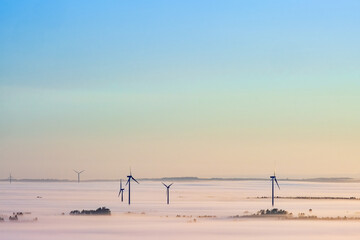Wind turbines above the morning mist at dawn