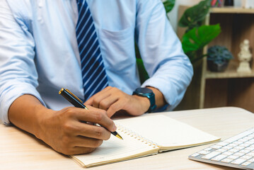 Man hand holding pen write note diary on book.