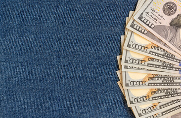 A stack of money on a background of denim. Banknotes are partially visible.