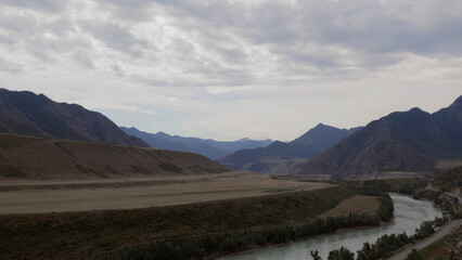 Mountains valley of Altai with blue Katun river under dramatic sky