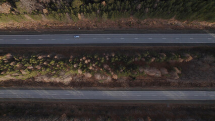 Traffic cars on multiple lane highway road between deep forest