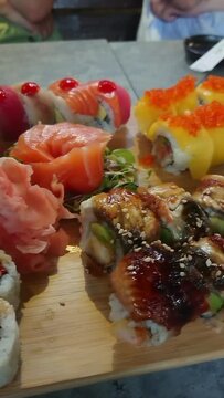Set of colorful different kinds of sushi rolls placed on wooden board.