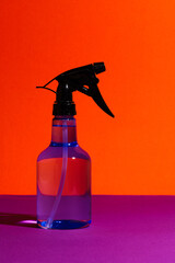 Isolated Transparent Sprayer Bottle on Vibrant Orange Background