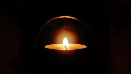 Closeup of a lit candle in the dark room
