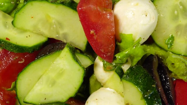 Slide shot of summer salad. Slow Macro Dolly Salads with Tomatoes, Cucumbers, Olives and Lettuce Leaves and Olive Oil. Element of keto diet for weight loss concept. Selective focus.