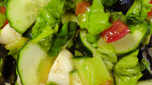 Slide shot of summer salad. Slow Macro Dolly Salads with Tomatoes, Cucumbers, Olives and Lettuce Leaves and Olive Oil. Element of keto diet for weight loss concept. Selective focus.