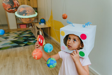 Little girl playing with paper spaceship learning Solar system planets