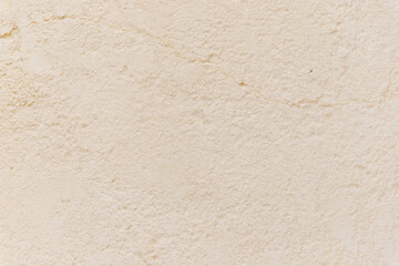 The wall is beige or white. Small cracks on the surface. Texture and background. The old wall. The wall is painted with paint.
