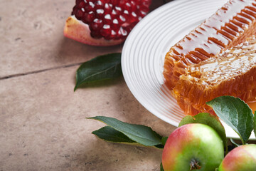 Rosh Hashanah. Honey jar, honeycomb, apple and pomegranate on light beige old rustic concrete background table. Jewish New Year holiday greeting card. Rosh Hashanah holiday attributes. Space for text