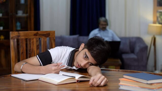 A teenage boy uninterested in studying - hates studying  hates school work  final exam pressure  lazy boy. An exhausted male student is feeling sleepy / yawning while studying - bored student  bori...