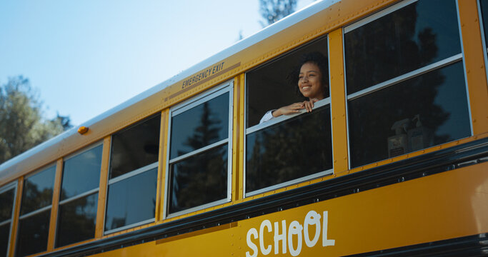 African American Girl Looking Out Of Schoolbus Window. Pupil Standing In Bus.