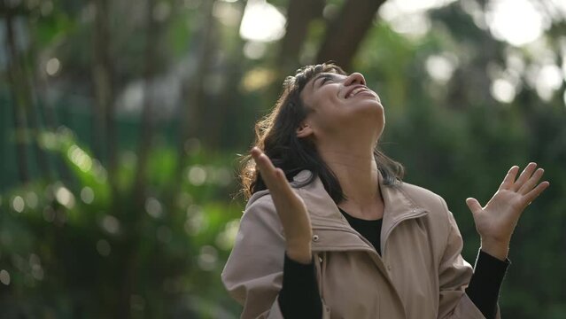 Evangelical South American woman standing outside feeling the presence of God arms in the air looking at sky with FAITH