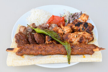 Grilled Turkish Adana, Urfa  Kebab with grilled vegetables, onion and rice on plate. Adana durum.