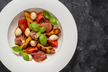 Grilled peach salad with mozzarella, prosciutto ham, red tomato, green basil and soy sauce