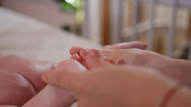 Sweet newborn baby from the back and bottom close up. Mom applies the cream to the baby's skin. Health and skin care, baby development concept. Slow motion 4K video