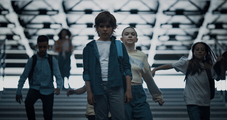 Upset schoolboy stand alone with backpack on stairway. Diverse children running.