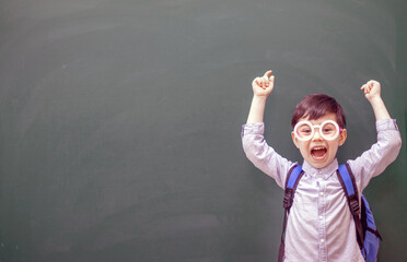 happy kid with party decorative glasses pointing indicates on empty no text green color blackboard...