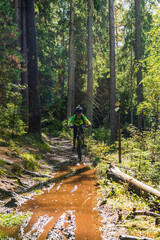 Boy cycling mountain bike on muddy forest trail