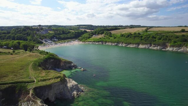 Aerial Shot Reversing Away From Busy Beach With Tourists To Reveal Rocky Coastline In Cornwall, UK