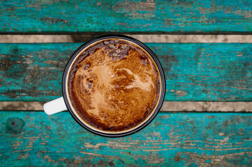 Cup, pot with coffee in enamel on wooden rustic table, green surface, cozy coffee breakfast, vintage style, side view, top view