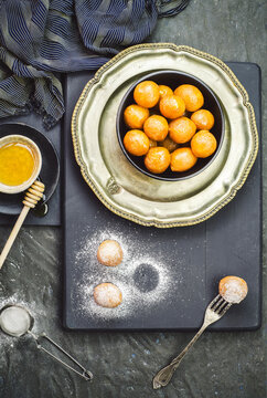 Arabic Cuisine; Middle Eastern dessert/Ramadan dessert Zalabya, or luqmat Al- Kadi served with honey and sugar on dark background