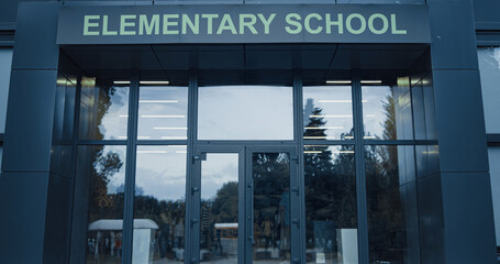 Elementary school exterior outside with closed door. Window reflecting sky trees