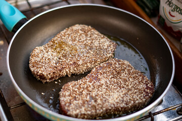 2 pepper steaks preparing in frying pan