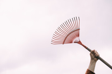 A man's hand holds a rake on a white background. Garden tools isolated on a neutral background.