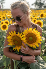 Beautiful woman in sunflower field at sunset enjoying summer nature. Attractive blonde with long healthy hair.